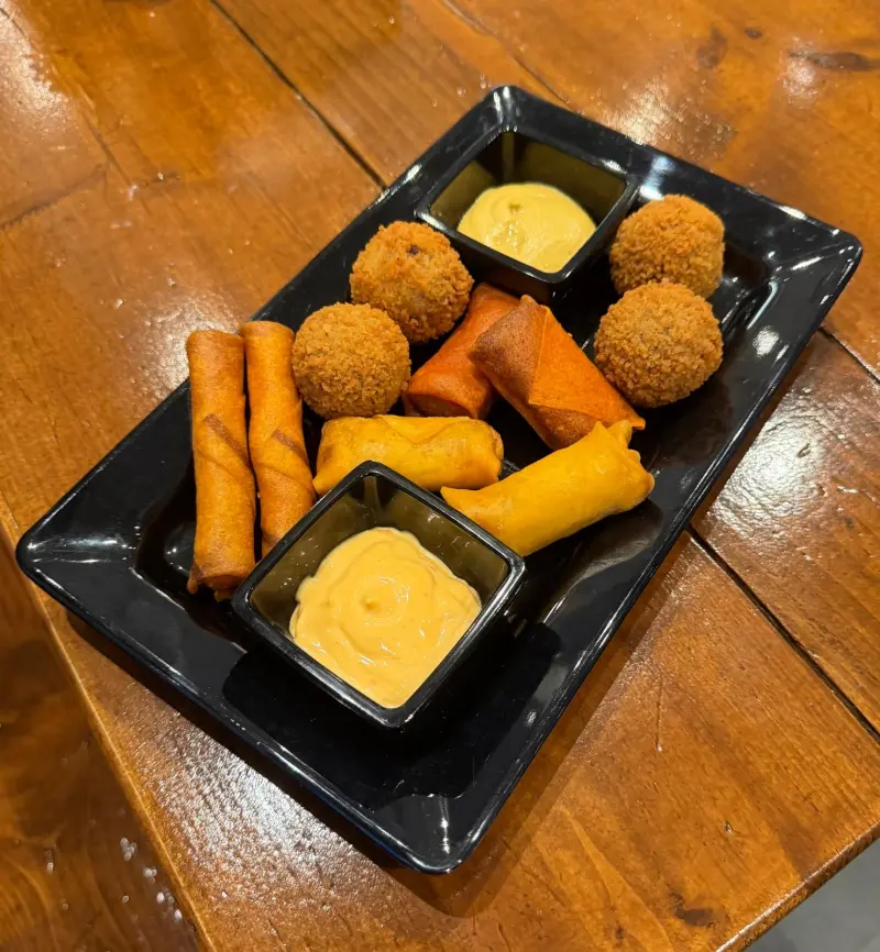 Een schaal met bitterballen, loempiaatjes en kaastengels met saus
